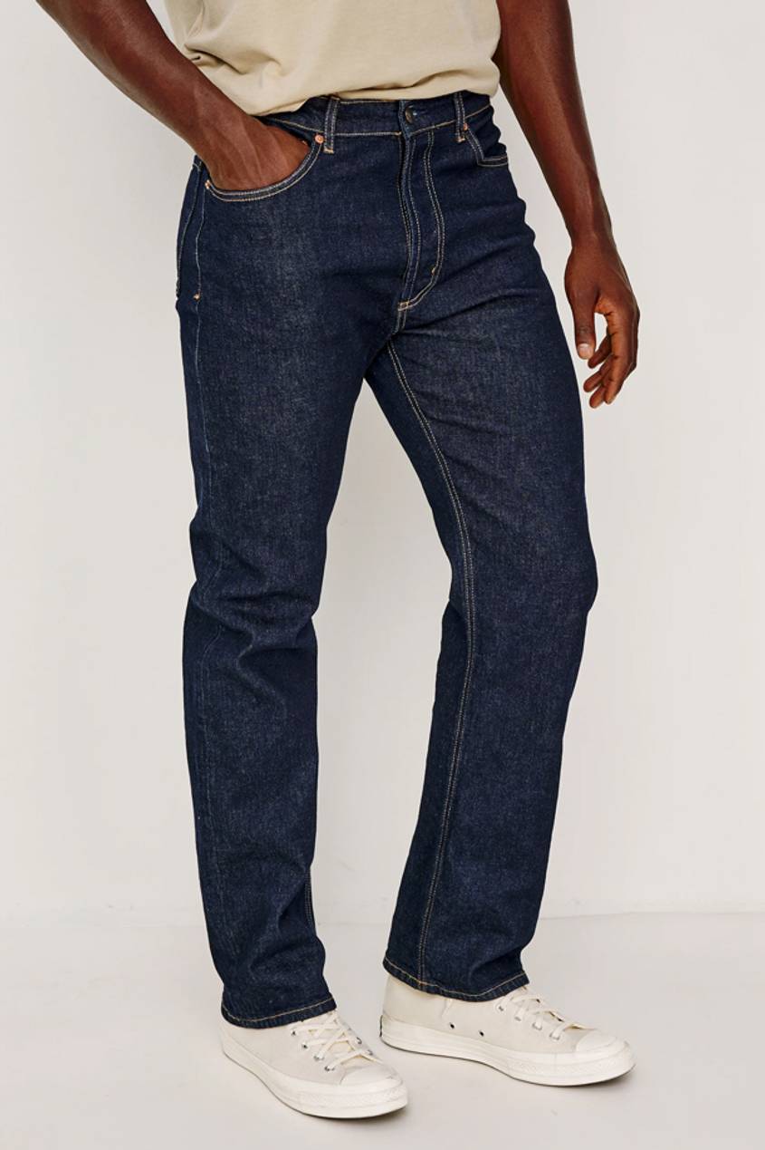 Front view image of a man wearing a dark pair of denim with his hand in his front pocket.