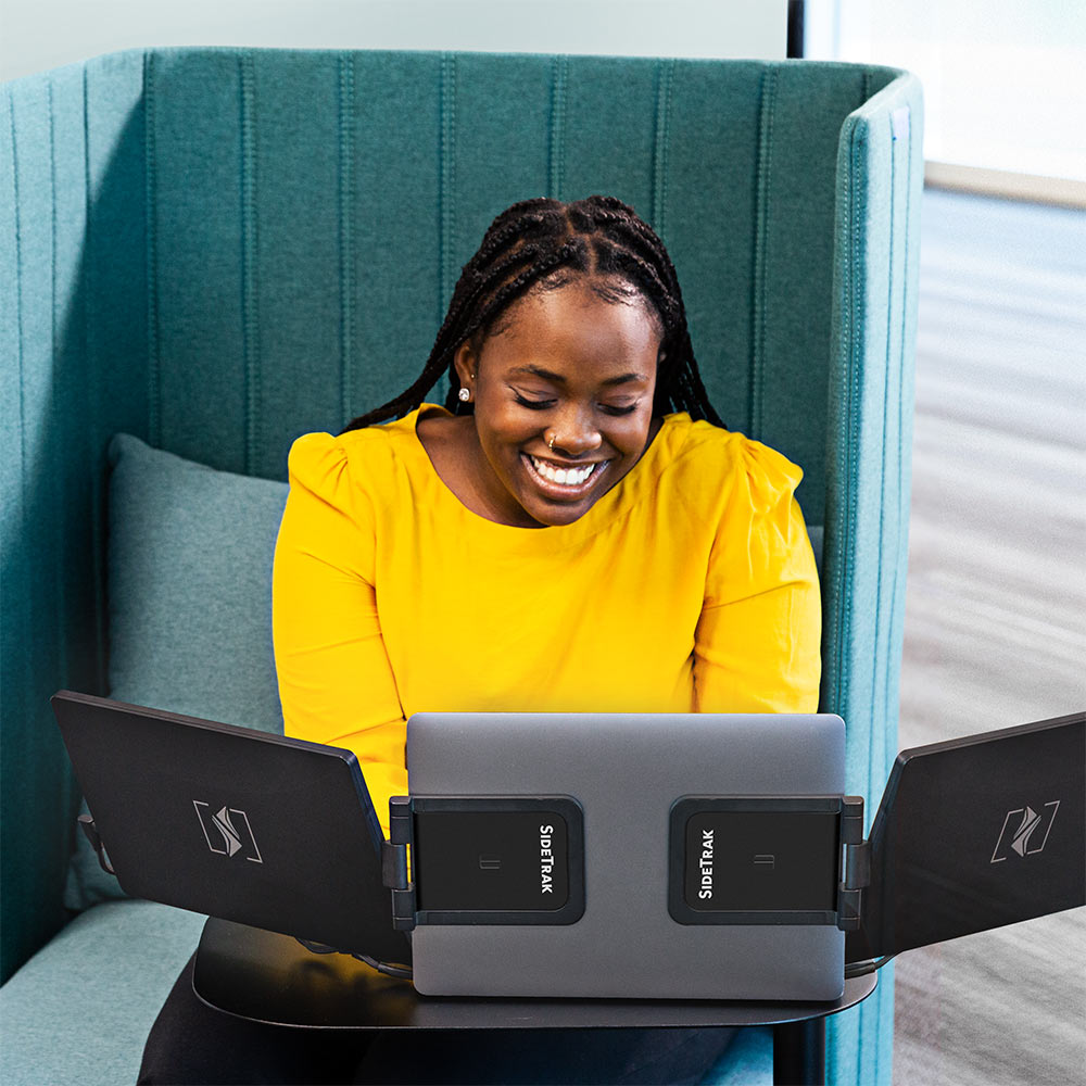 Woman working on a SideTrak swivel multi monitor set up