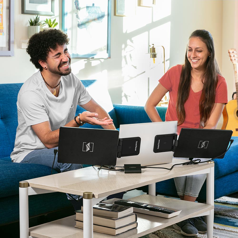 A couple both looking at a sidetrak swivel with hub multi monitor set up while in their apartment