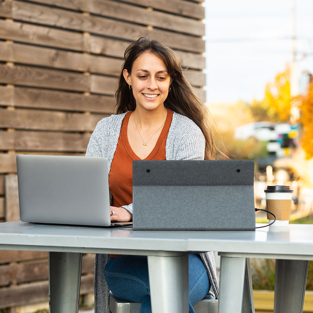 Solo  Econ  SideTrak  Travel Monitor  woman using a sidetrak solo travel monitor with a laptop for a dual screen set up