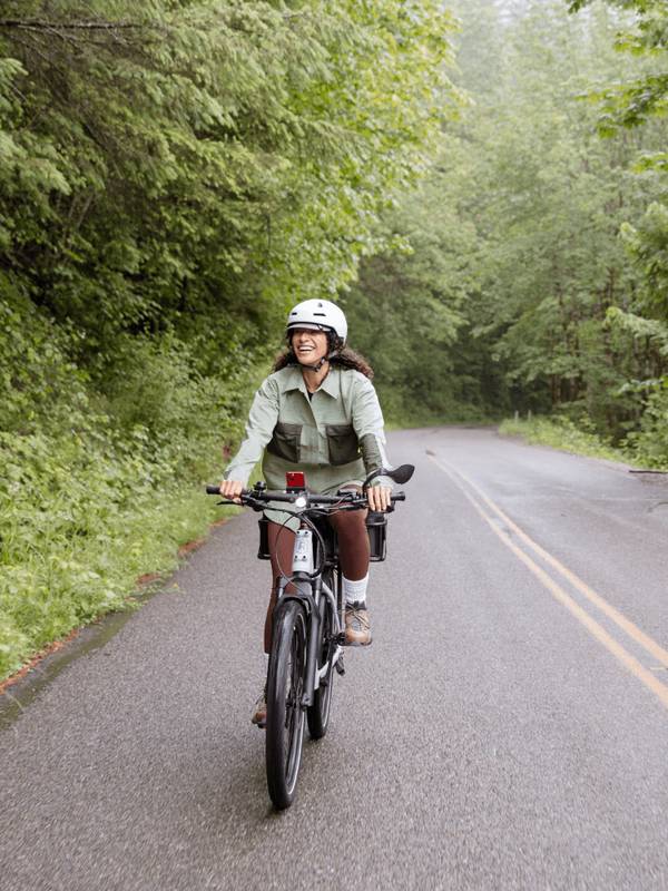 Woman riding the RadKick 7-Speed on a rural road. She is wearing a helmet & trees are in the background.