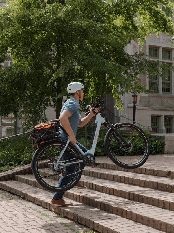 Man carrying the RadKick 7-Speed in Arctic Blue up a flight of stairs. He is wearing a helmet. 