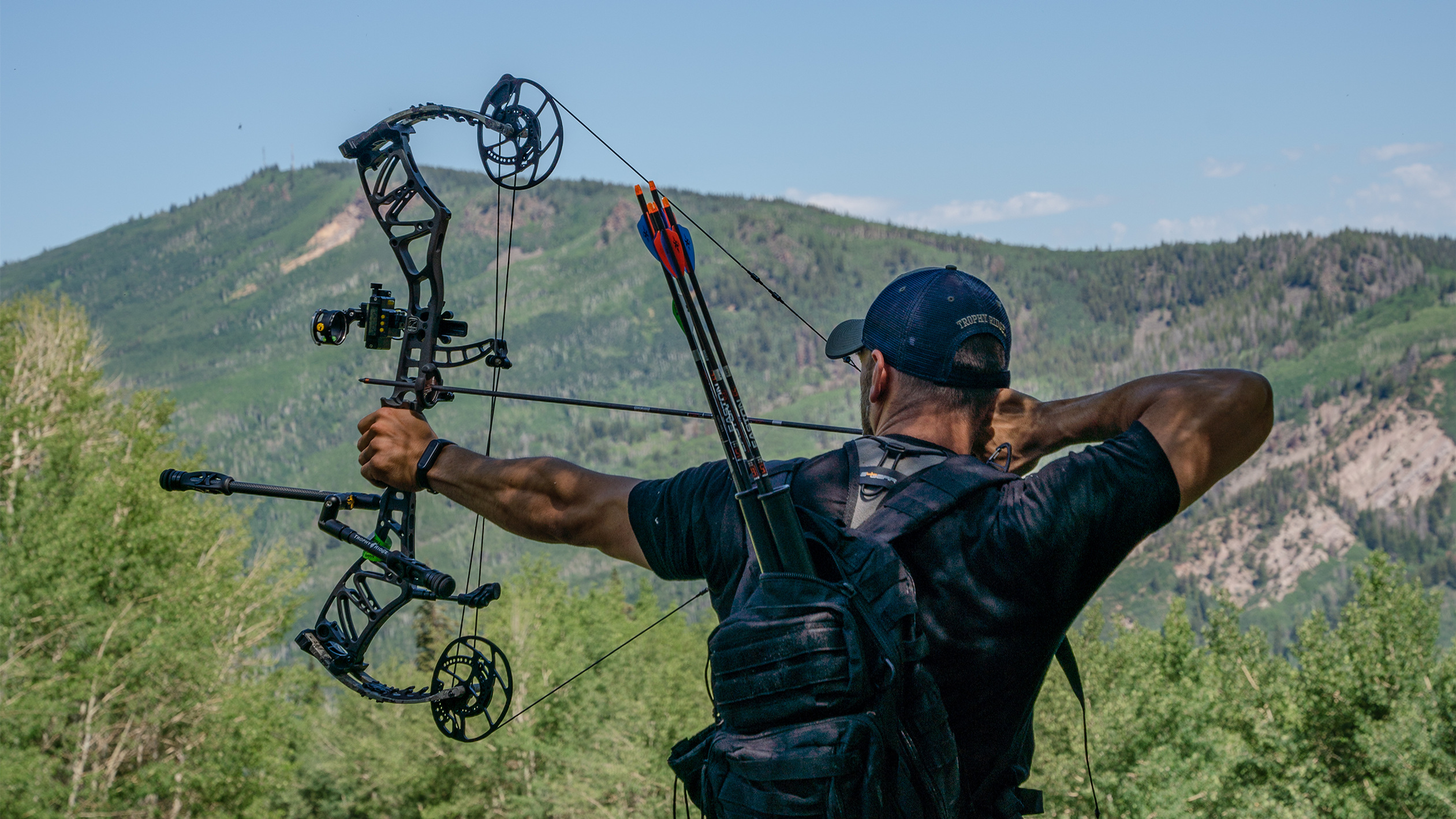 Man looking through a Trophy Ridge Digital React® One Pin Bow Sight as he draws back a Bear Archery Bow