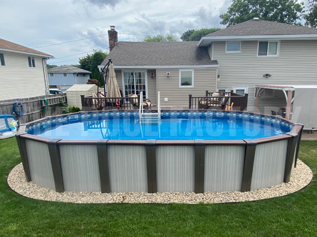 Oval above ground swimming pool with landscaping stones and a small deck for easy access