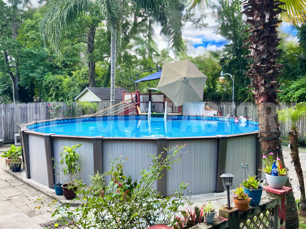 Round above ground swimming pool with a backdrop of tall palm trees