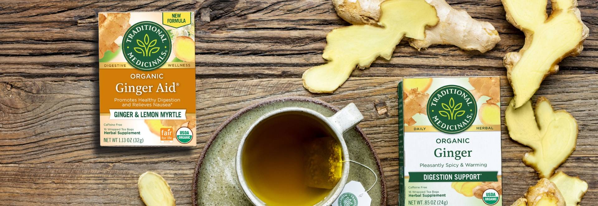 Traditional Medicinals Ginger Aid and Ginger tea boxes on table with ginger and tea cup