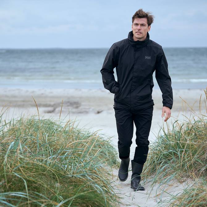 Man walking in beach shrub wearing a black Dubliner rain jacket.