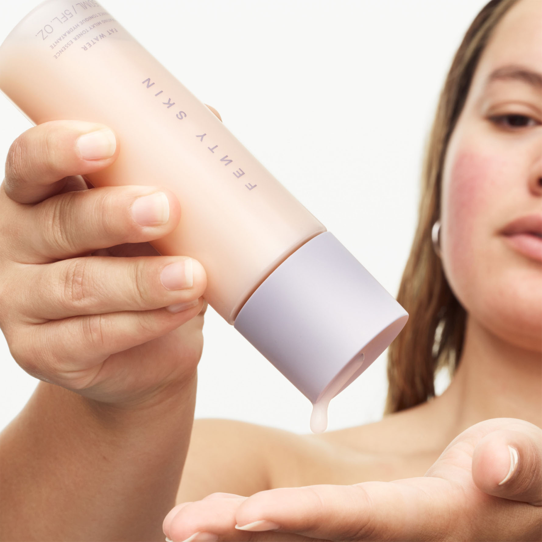 Model squeezing Fat Water Milky Toner Essence into hands,