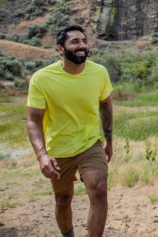 Man trail hiking while wearing the Light Lime SolarSwift Short Sleeve Shirt by Beyond Clothing.