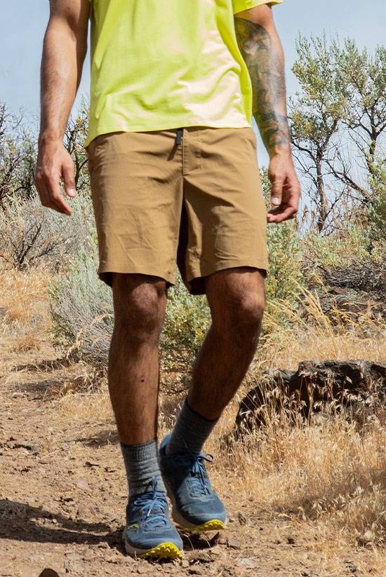 Man wearing the Tobacco colored TarnGood shorts and the Light Lime SolarSwift Tech-T while hiking through the high desert.