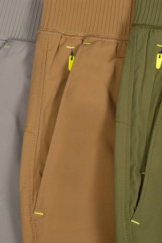 close up image of the zippered right hand pocket of the Tinkham pants. Featuring each color: Moonstone, Tobacco and Evergreen.