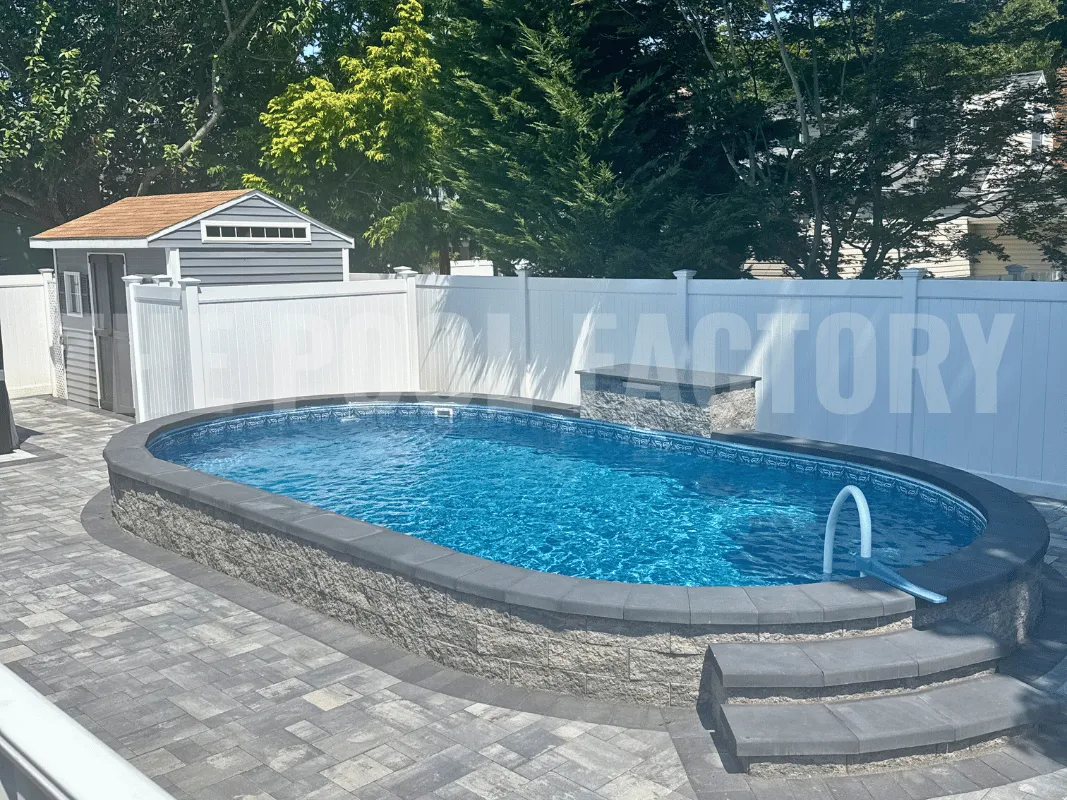 Semi-inground swimming pool surrounded by elegant paver stone patio and privacy fence