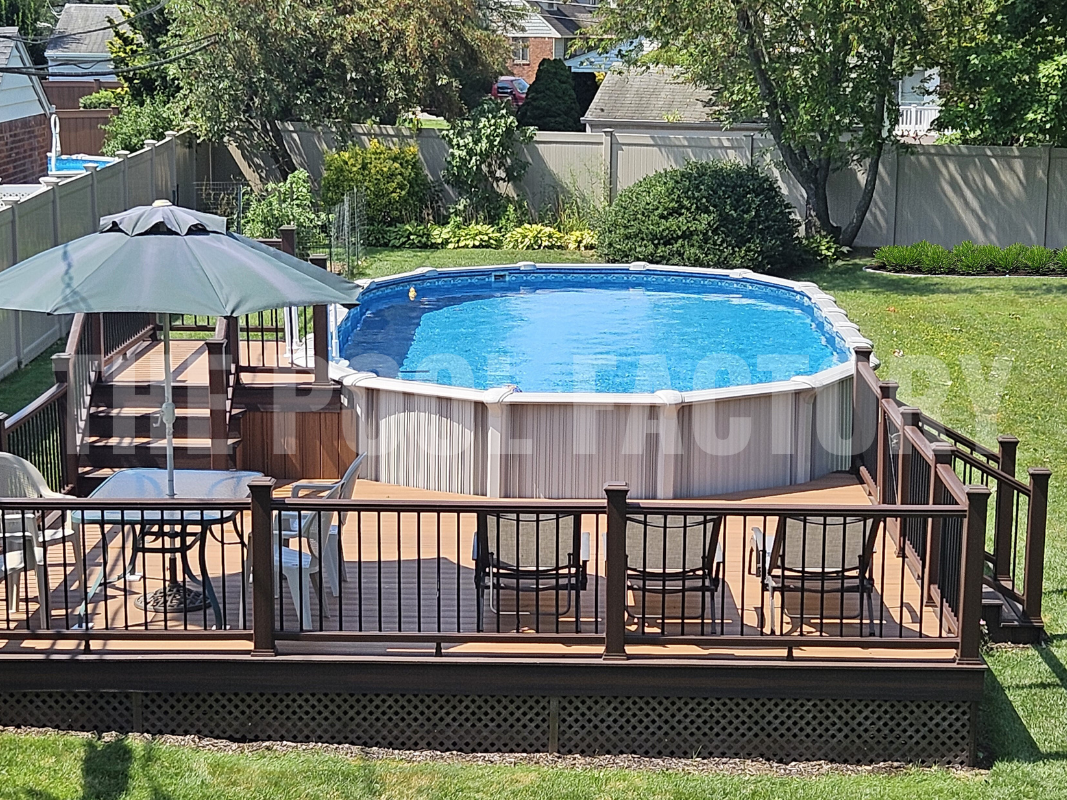 Oval swimming pool with partial deck, landscaping and patio furniture