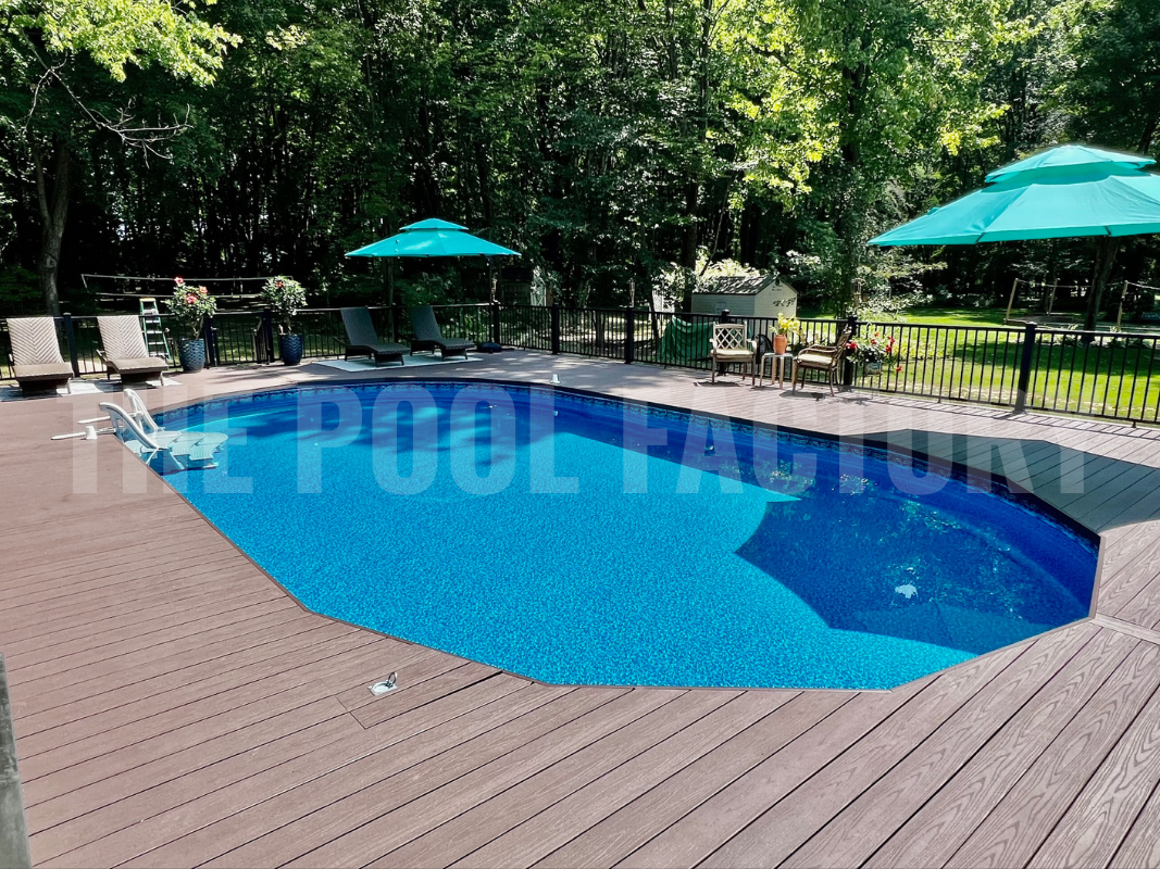 Oval semi-inground pool with full deck surrounded by lush greenery