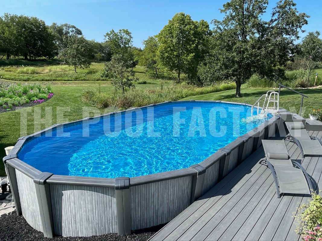 Oval above ground swimming pool with deck, lounge seating, lush greenery on a bright sunny day