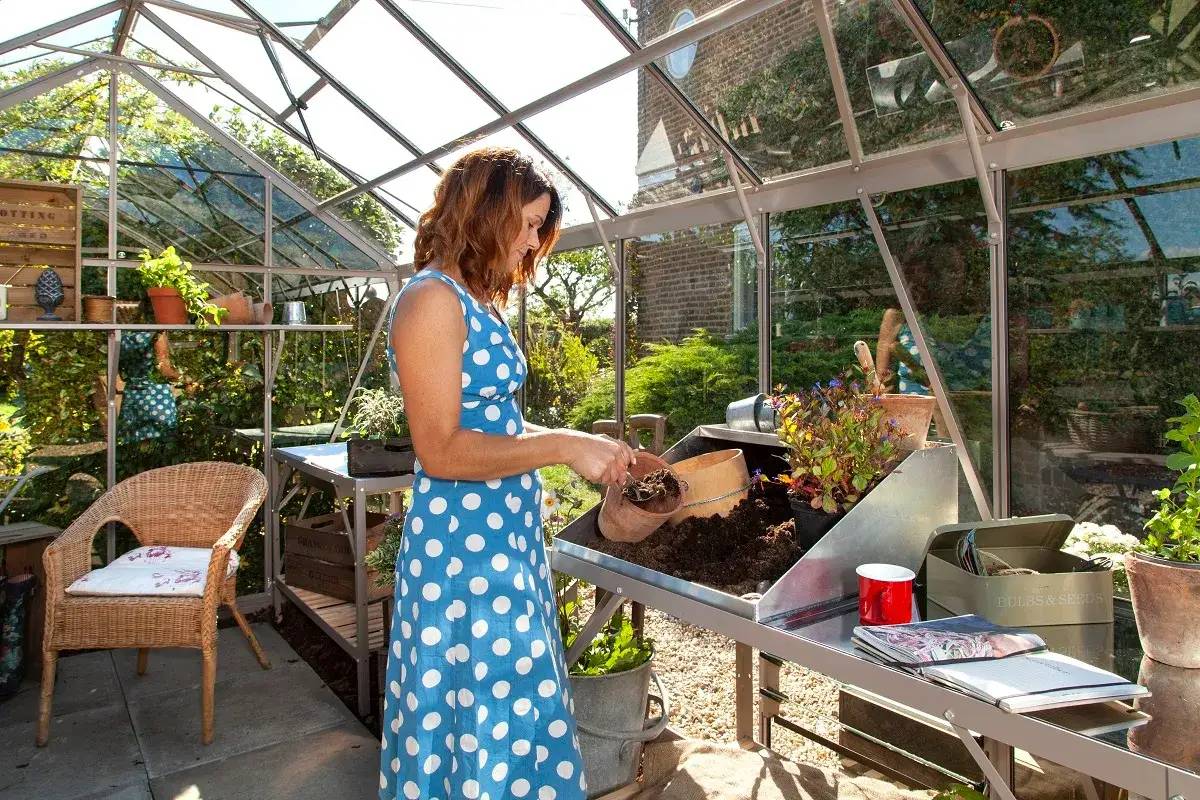 Lady potting up plants inside her Rhino Greenhouse with a reservoir
