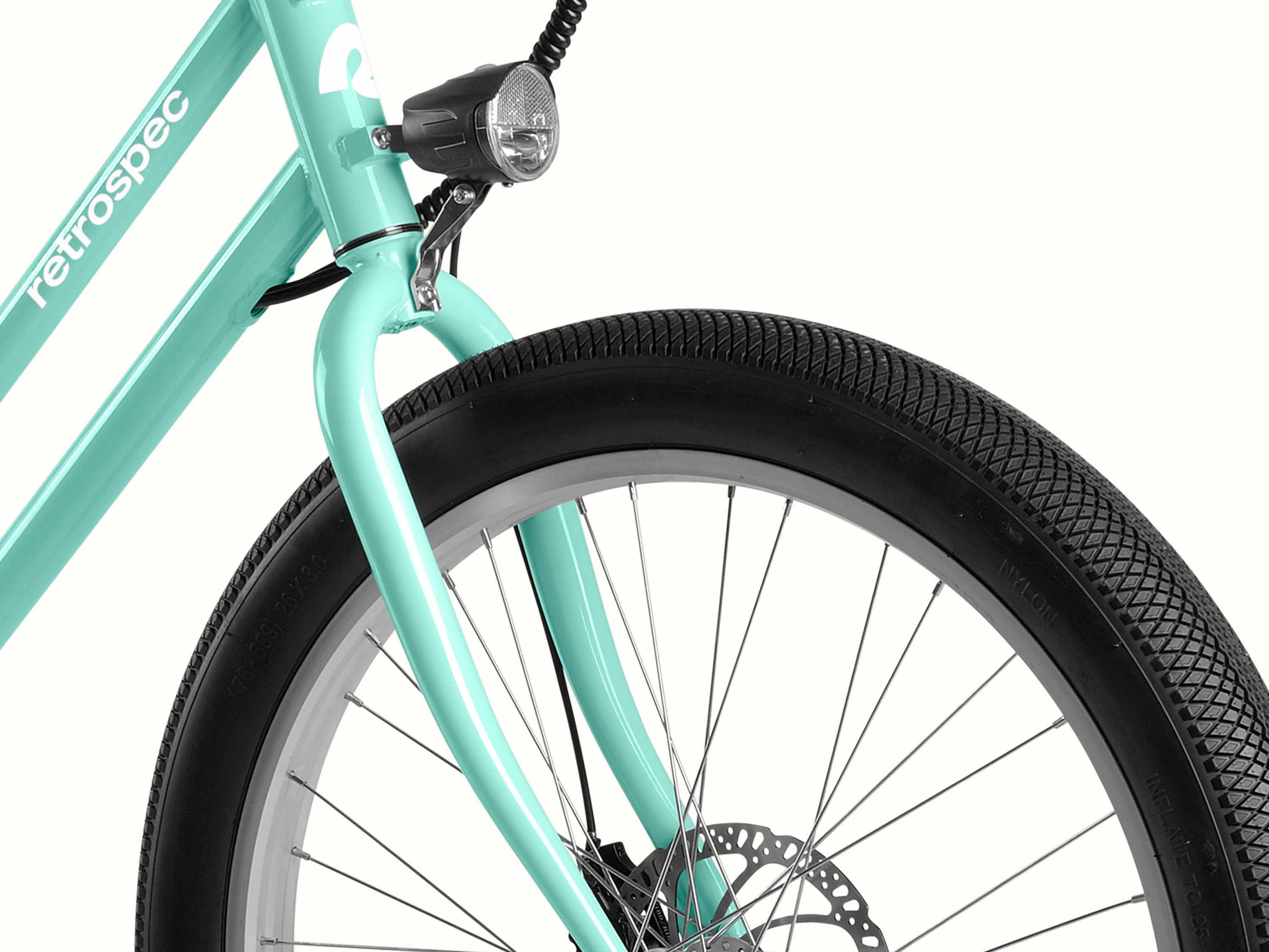 Close-up of a turquoise electric bicycle's front wheel, fork, and headlight, with brand 