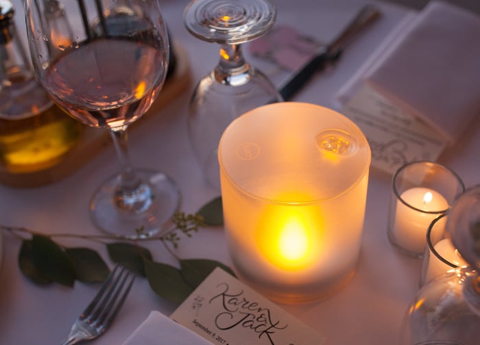 A beautifully set table featuring a glowing candle, wine glasses, and elegant place settings.
