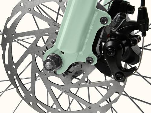 Close-up of the Chatham Rev+ 2 Beach Cruiser Electric Bike - Step Through's front disc brake, featuring a mint green fork, metallic rotor, and black caliper assembly.