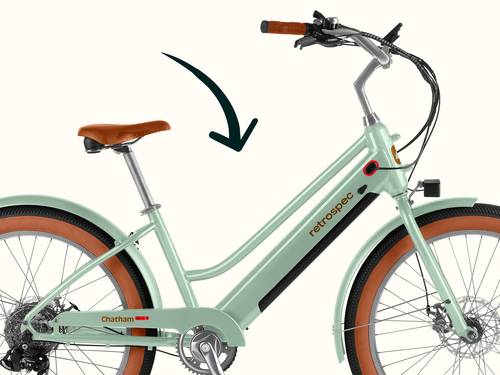 A mint green retro-style Chatham Rev+ 2 Beach Cruiser Electric Bike with a black drawn arrow pointing to the step through frame and showcasing the comfortable upright seated position.