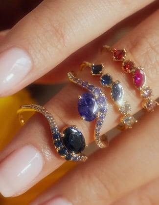 Close up of four gold gemstone rings stacked on a finger