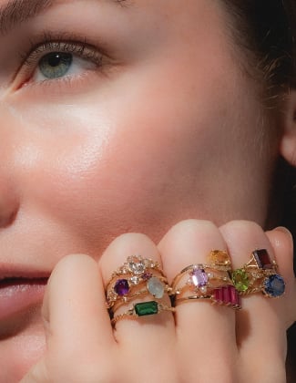 Close up of a woman's hand wearing several gold gemstone rings