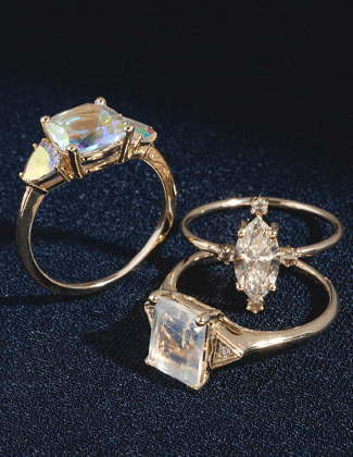 A close up of three gold gemstone rings laying on a black background
