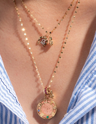 Close up shot of a woman wearing two layered gold charm necklaces
