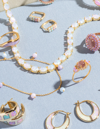 An assortment of pastel opal jewelry laying on a light blue background