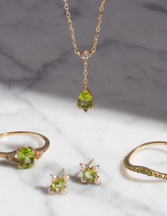 Two gold rings, a gold necklace, and gold earrings with green peridot gemstones