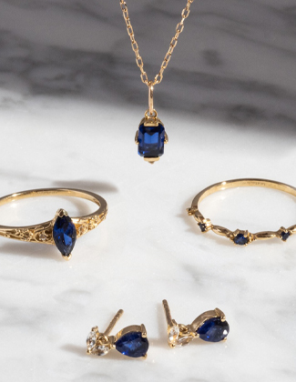 Two gold rings, a gold necklace, and gold earrings with blue sapphire gemstones