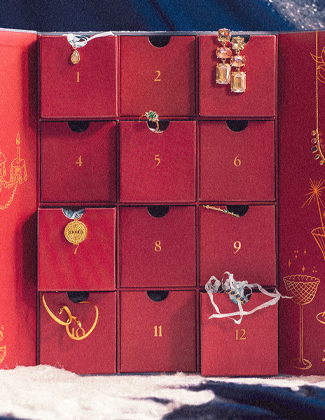 A red advent claendar box opened with jewelry hanging out of the compartments
