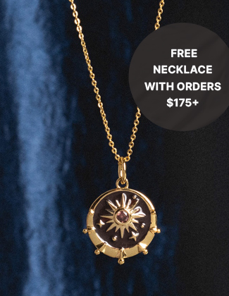 A gold celestial pendant necklace hanging in front of a blue background