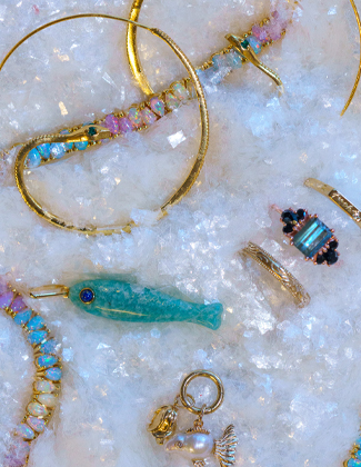 Assorted gold gemstone jewelry laying in a bed of faux snow with a badge that reads 20% off