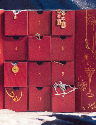 An assortment of gold gemstone jewelry laying in faux snow with a red badge that reads 20% off everything