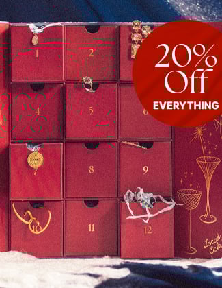 An open red advent calendar with number compartments and assorted gold jewelry hanging out with a badge that reads 20% offA close up of several gold gemstone rings in a red velvet ring tray