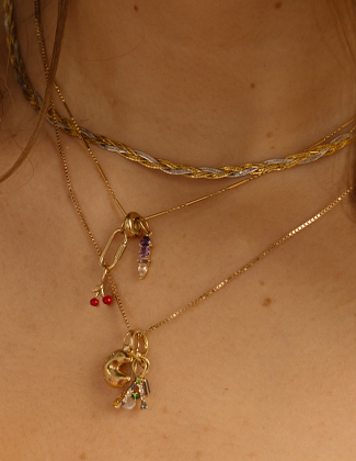 Close up of gold charm necklaces worn on a woman's neck