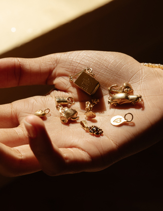 A hand holding several vintage gold charms