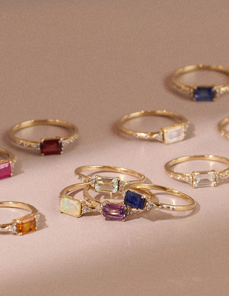 Gold gemstone rings laying on a pale pink surface