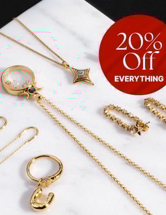 Assorted gold jewelry laying on a white marble slab with a badge that reads 20% off