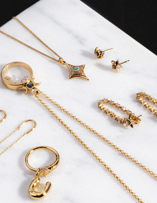 Assorted gold jewelry laying on a white marble slab with a badge that reads 20% off