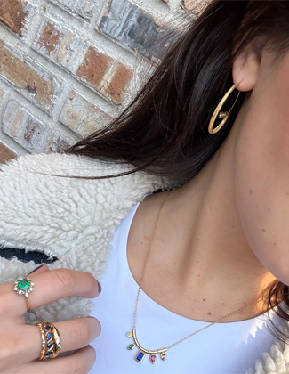 Close up of a woman wearing a white shirt wearing stacks of gold jewelry