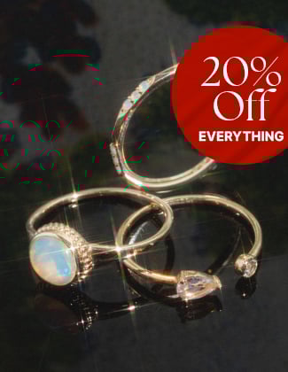 Three gold gemstone rings laying on a black background with a badge that reads 20% off