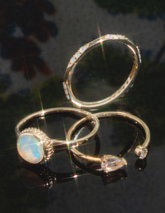 Three gold gemstone rings laying on a black background with a badge that reads 20% off