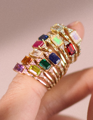 Several gold gemstone rings stacked on a finger