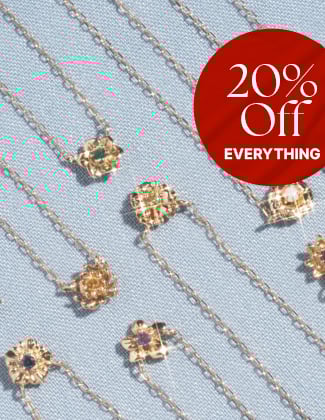 Gold flower pendant necklaces laying on a light blue background with a badge that reads 20% off
