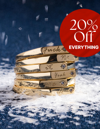 A stack of gold rings engraved with words on a snowy surface with dark blue background