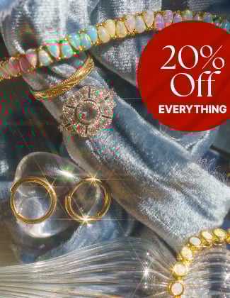 Assorted gold gemstone jewelry laying on a crushed light blue velvet backdrop with a badge that reads 20% off