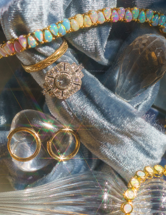 Assorted gold gemstone jewelry laying on a crushed light blue velvet backdrop with a badge that reads 20% off