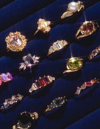 Several gold gemstone rings sitting in a jewelry tray with dark blue fabric
